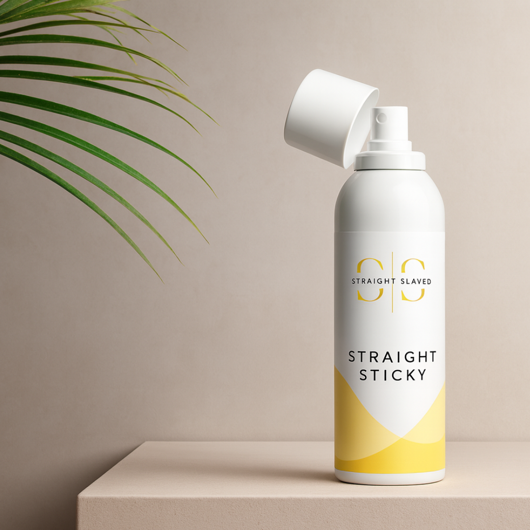 White spray bottle labeled 'Straight Sticky' on a beige surface with a plant in the corner.